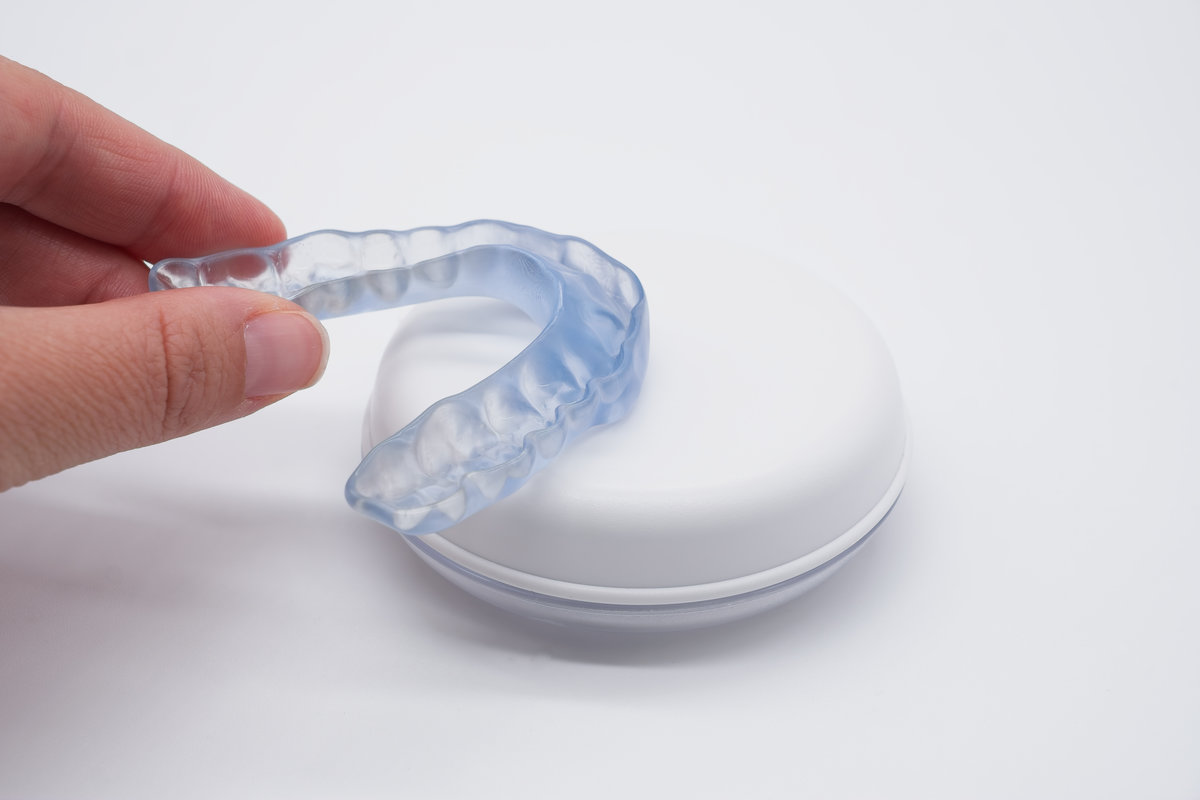 Doctor holding transparent dental night guard or mouthguard over its case
