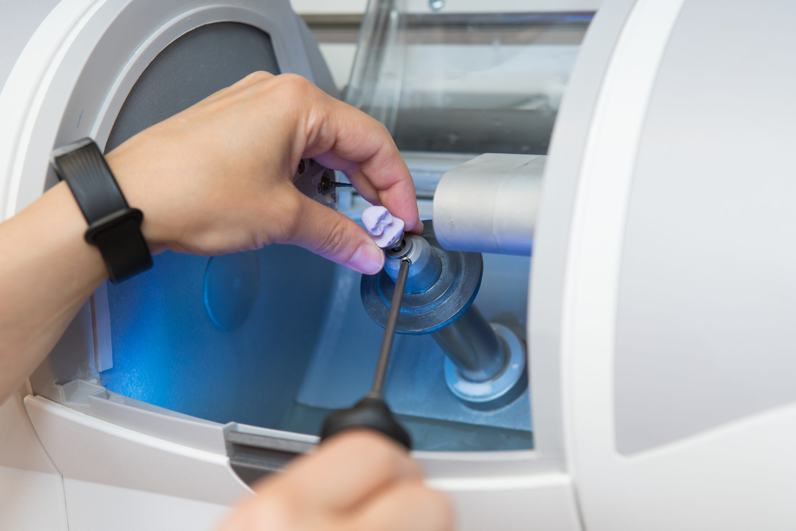 woman sets a workpiece in a dental milling machine for the manufacture of a dental crown